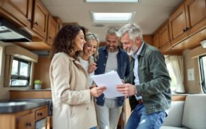 Un couple examine l'intérieur d'un camping-car d'occasion en tenant une checklist, ouvrant des placards et vérifiant les équipements, baigné par une lumière naturelle chaude entrant par les fenêtres.